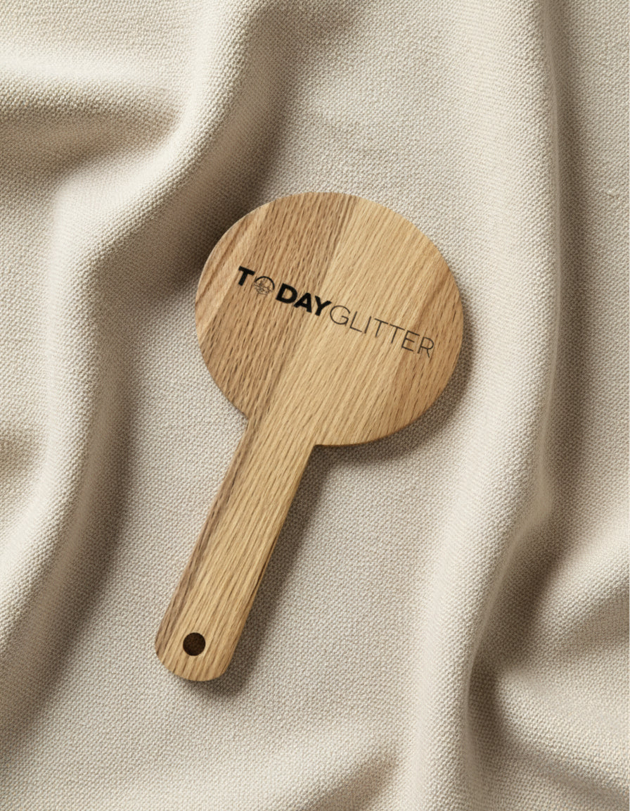 Today Glitter wooden handheld mirror resting on soft beige fabric – sustainable beauty accessory with clean minimalist design.